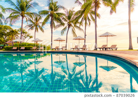 Umbrella and chair around swimming pool in resort hotel for leisure travel and vacation neary sea ocean beach 87039026