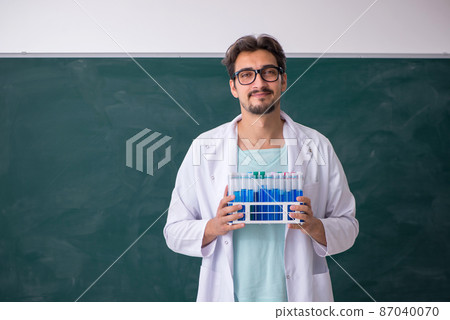 Young male chemist in front of blackboard 87040070