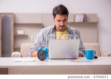 Young male freelancer in time management concept at home 87040071