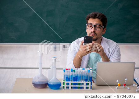 Young male chemist in front of blackboard Young male chemist in front of blackboard 87040072