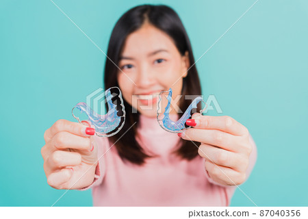 woman smiling hold silicone orthodontic retainers for teeth 87040356