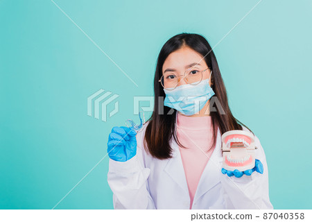 woman dentist holding silicone orthodontic retainers and model teeth denture 87040358