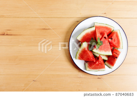 Fresh red watermelon slices in white plate on wooden background. 87040683