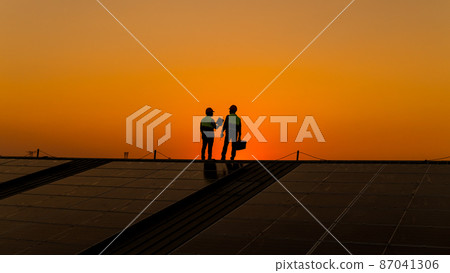Engineers walking on roof inspect and check solar cell panel by hold equipment box and radio communication ,solar cell is smart grid ecology energy sunlight alternative power factory concept Engineers walking on roof inspect and check solar cell panel by hold equipment box and radio communication ,solar cell is smart grid ecology energy sunlight alternative power factory concept 87041306