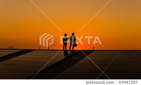 Engineers walking on roof inspect and check solar cell panel by hold equipment box and radio communication ,solar cell is smart grid ecology energy sunlight alternative power factory concept 87041307