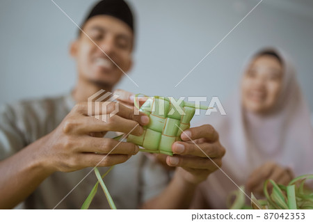 muslim couple asian making ketupat rice cake at home using palm leaf 87042353