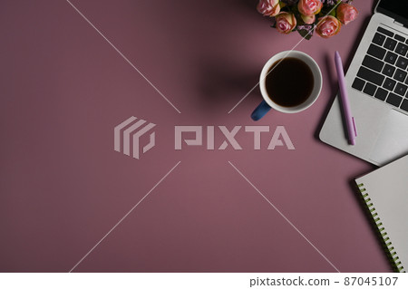 Cup of coffee, laptop computer, notebook and flower pot on purple background. 87045107