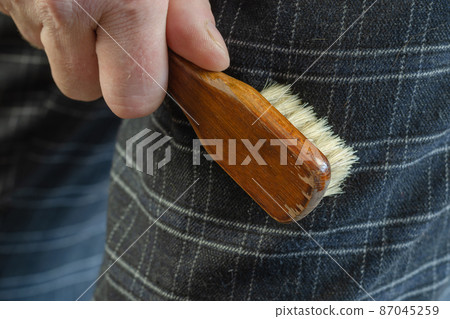 A mature man cleans his pants with a brush. A mature man cleans his pants with a brush. 87045259