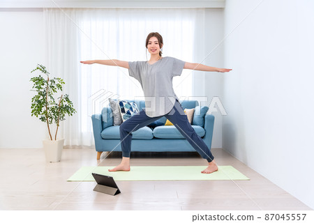 Young woman doing online yoga at home Young woman doing online yoga at home 87045557