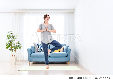 Young woman doing online yoga at home 87045565