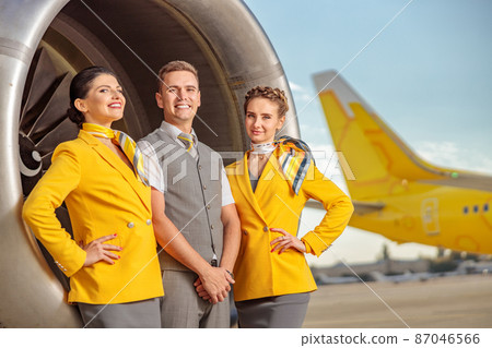 Joyful airline workers standing near aircraft engine Joyful airline workers standing near aircraft engine 87046566