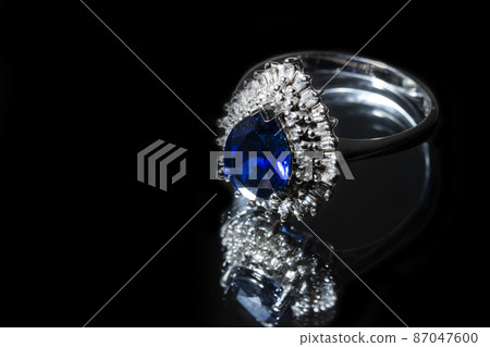jewelry gold ring with a large blue sapphire and diamonds on a black background with reflection jewelry gold ring with a large blue sapphire and diamonds on a black background with reflection 87047600