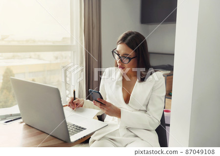 Businesswoman working on laptop computer. Woman sitting at office managing her business 87049108