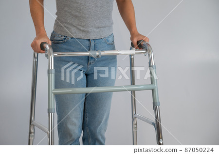 A woman is walking with a walker on a white background A woman is walking with a walker on a white background 87050224