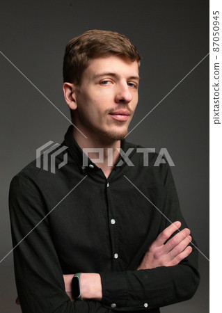 Blond man in black isolated on dark grey Blond man in black isolated on dark grey 87050945