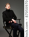 Blond man in black isolated on dark grey 87050970