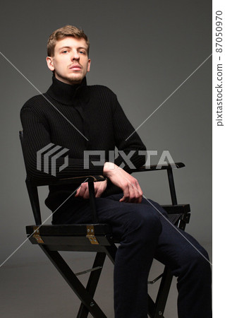 Blond man in black isolated on dark grey Blond man in black isolated on dark grey 87050970