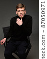 Blond man in black isolated on dark grey 87050971