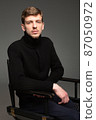 Blond man in black isolated on dark grey 87050972