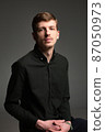 Blond man in black isolated on dark grey 87050973