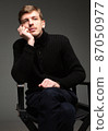 Blond man in black isolated on dark grey 87050977