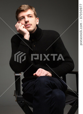 Blond man in black isolated on dark grey 87050977