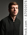 Blond man in black isolated on dark grey 87050978