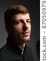 Blond man in black isolated on black 87050979