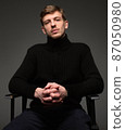 Blond man in black isolated on dark grey 87050980