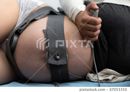 Close Up Pregnant Woman On Hospital Couch During Medical Control Cardiotocography. Visit Gynecologist Doctor At Clinic For Pregnancy Consultant. Examine Expectant Belly Baby Mother Healthcare Check Up 87053350