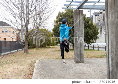 A man doing a preparatory exercise before jogging as a hobby A man doing a preparatory exercise before jogging as a hobby 87054036