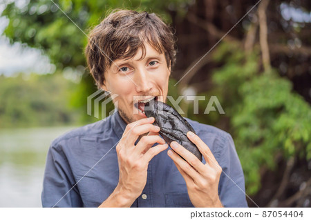 Man eating Vietnamese Pork Banh Mi Sandwich in a black baguette Man eating Vietnamese Pork Banh Mi Sandwich in a black baguette 87054404