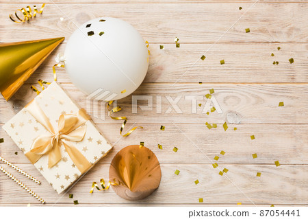 Holiday background with colorful balloon, gift and confetti. Flat lay style. Birthday or party greeting card with copy space Holiday background with colorful balloon, gift and confetti. Flat lay style. Birthday or party greeting card with copy space 87054441
