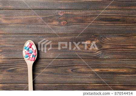 Vitamin capsules in a wooden spoon on a colored background. Pills served as a healthy meal. Drugs, pharmacy, medicine or medical healthycare concept 87054454
