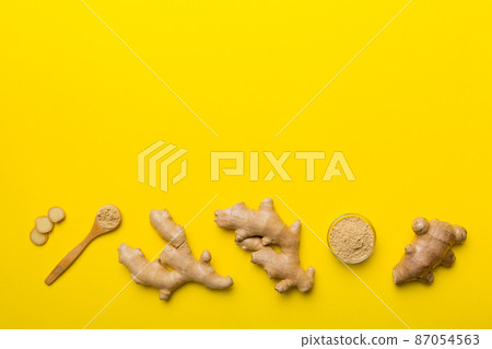 Finely dry Ginger powder in bowl with green leaves isolated on colored background. top view flat lay 87054563