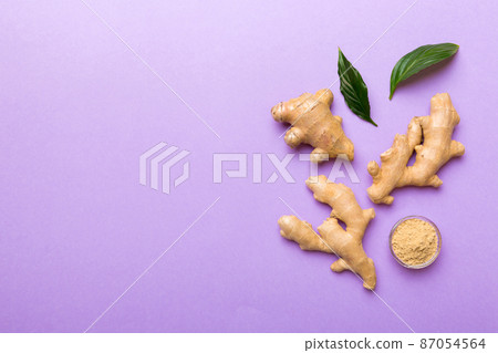 Finely dry Ginger powder in bowl with green leaves isolated on colored background. top view flat lay 87054564
