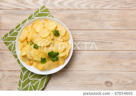 Potato chips on bowl with napkin on colored background. Delicious crispy potato chips in bowl. Space for text. Top view 87054605