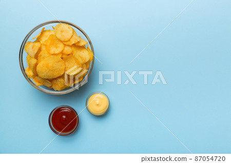 Top view chips with sause in bowl on colored background, top view with copy space Top view chips with sause in bowl on colored background, top view with copy space 87054720