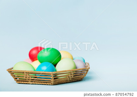 Multi colors Easter eggs in the woven basket on colored background . Pastel color Easter eggs. holiday concept with copy space Multi colors Easter eggs in the woven basket on colored background . Pastel color Easter eggs. holiday concept with copy space 87054792