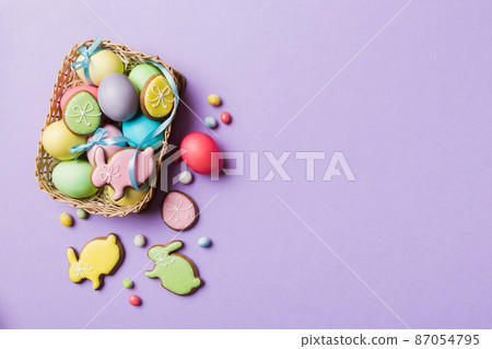 Colorful easter cookies in basket with Multi colors Easter eggs on colored background . Pastel color Easter eggs. holiday concept with copy space Colorful easter cookies in basket with Multi colors Easter eggs on colored background . Pastel color Easter eggs. holiday concept with copy space 87054795