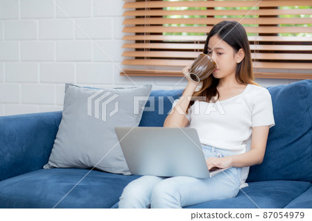 Young asian business woman smile and work from home with laptop computer online on sofa. Young asian business woman smile and work from home with laptop computer online on sofa. 87054979