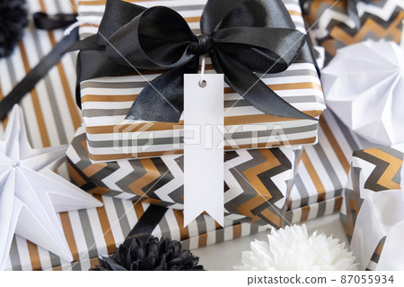 Wrapped present with blank vertical gift tag and black bow close up, label Mockup 87055934