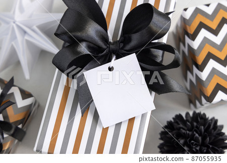 Wrapped present with blank square gift tag and black bow close up, label Mockup 87055935