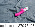 Vibrating sex toy lying on crumpled mattress. 87057193