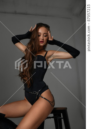 Pretty female with dark hair in a black swimsuit sit on chair. vamp woman Pretty female with dark hair in a black swimsuit sit on chair. vamp woman 87057215