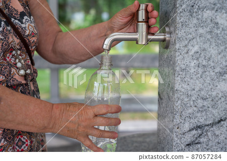 Woman pours water in plastic bottle. Close up Woman pours water in plastic bottle. Close up 87057284