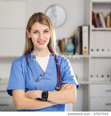 nurse standing in medical office with clipboard 87057429