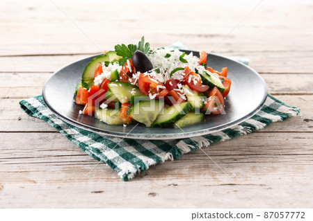 Traditional Bulgarian shopska salad with tomato,cucumber and bulgarian sirene cheese on wooden table 87057772