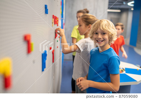 Boy smiling at camera playing lego with friends 87059080