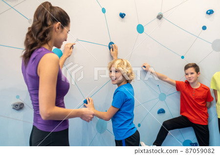 Boys near climbing wall looking at woman Boys near climbing wall looking at woman 87059082